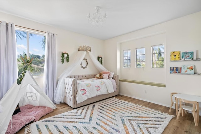 bedroom featuring multiple windows, a notable chandelier, and wood finished floors