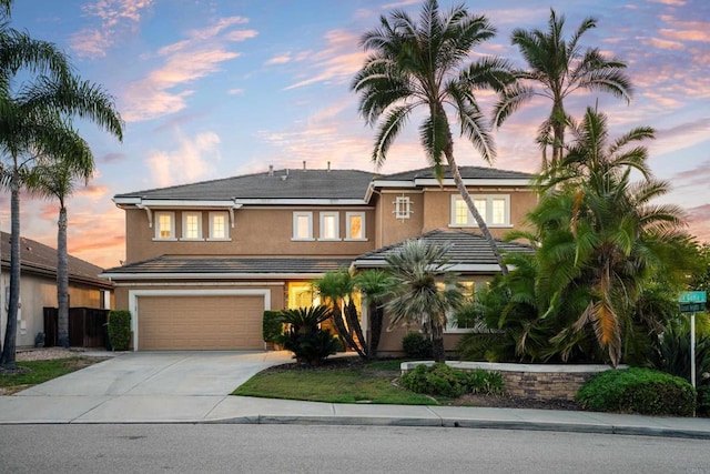 view of front of property with a garage, solar panels, driveway, a tiled roof, and stucco siding