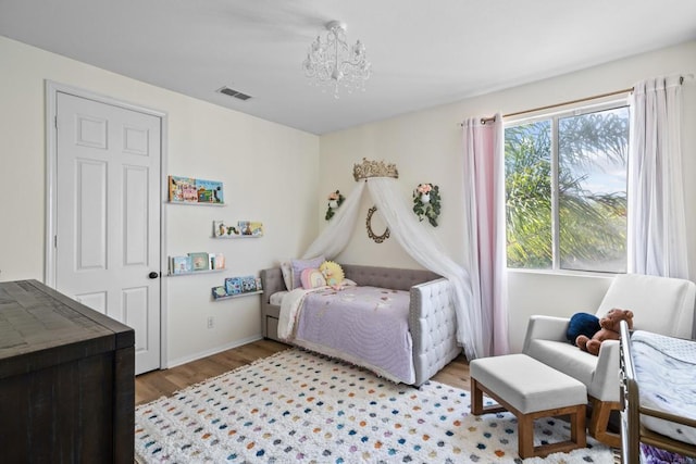 bedroom with a chandelier, baseboards, visible vents, and light wood-style floors