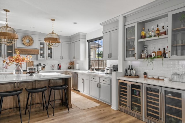 bar featuring light wood finished floors, dishwasher, wine cooler, decorative light fixtures, and a sink