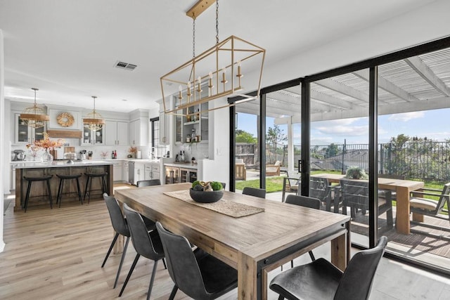 dining area with light wood finished floors and visible vents