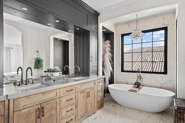 bathroom with double vanity, marble finish floor, a freestanding bath, and a sink