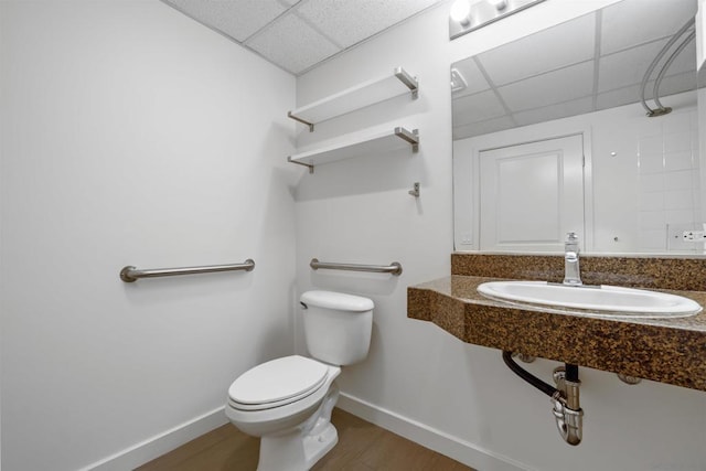 bathroom with wood-type flooring, sink, a drop ceiling, and toilet