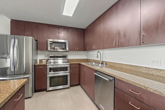 kitchen with sink, light stone counters, and stainless steel appliances