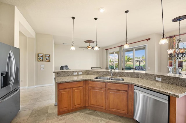 kitchen featuring sink, light stone counters, hanging light fixtures, and appliances with stainless steel finishes