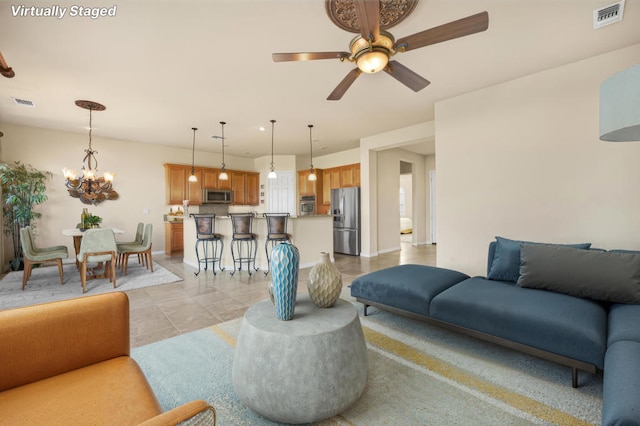 tiled living room featuring ceiling fan with notable chandelier