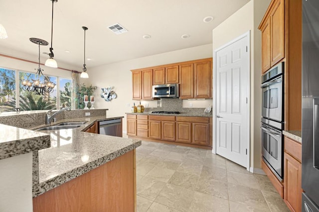 kitchen featuring tasteful backsplash, hanging light fixtures, sink, an inviting chandelier, and stainless steel appliances