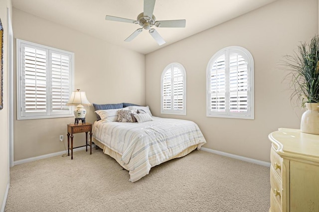 bedroom featuring ceiling fan, light colored carpet, and multiple windows