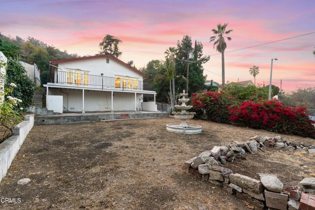 back house at dusk with a balcony