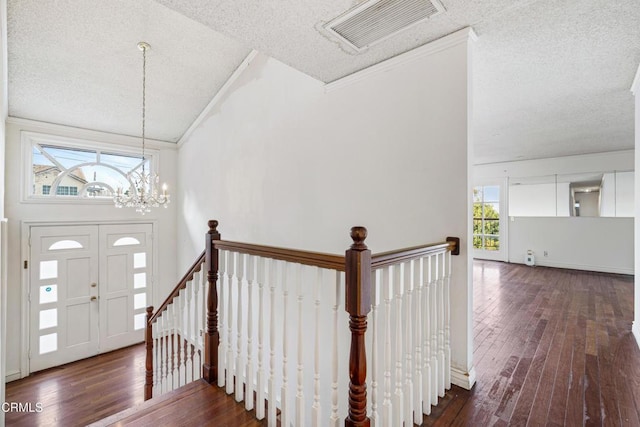 entrance foyer featuring a textured ceiling, dark wood-type flooring, an inviting chandelier, high vaulted ceiling, and crown molding