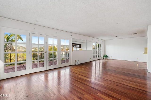 unfurnished living room with a textured ceiling, dark wood-type flooring, and french doors