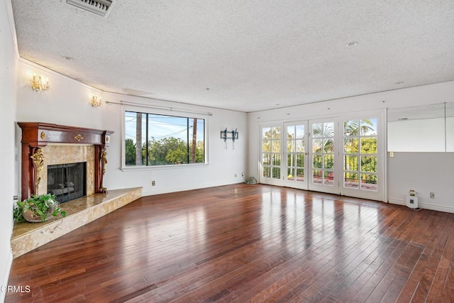 unfurnished living room featuring a premium fireplace, a textured ceiling, and hardwood / wood-style floors