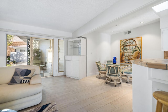 living room featuring light wood-type flooring and a textured ceiling