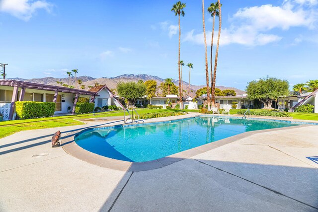 view of pool with a mountain view, a yard, and a patio