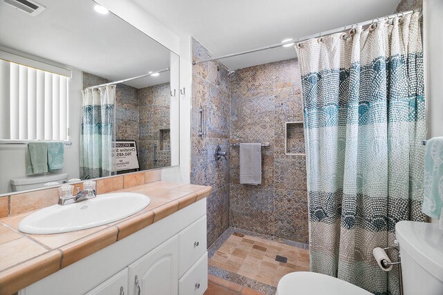 bathroom featuring toilet, walk in shower, and vanity