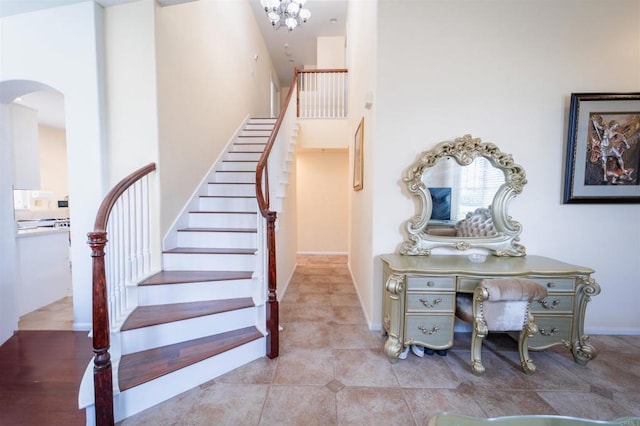 stairway with tile patterned floors and a towering ceiling