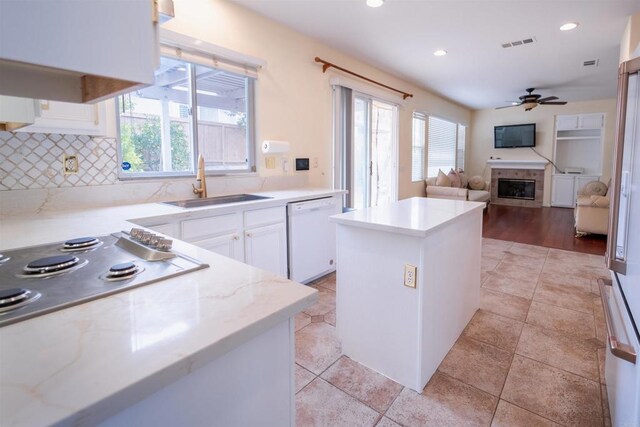 kitchen featuring ceiling fan, dishwasher, a kitchen island, sink, and white cabinetry