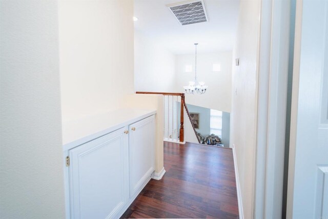 hall featuring dark wood-type flooring and an inviting chandelier