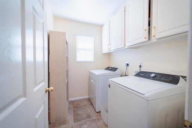 clothes washing area with washer and clothes dryer, light tile patterned floors, and cabinets