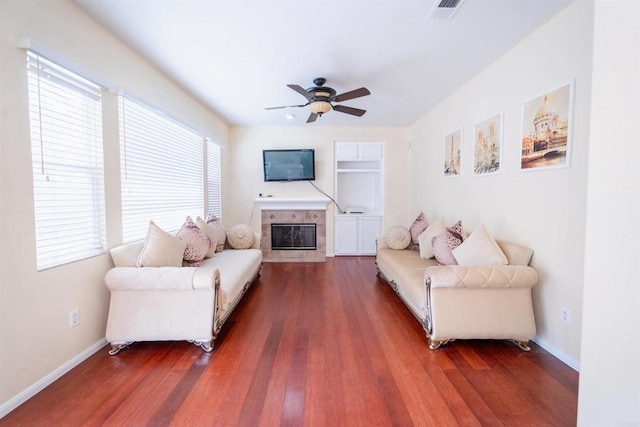 living room featuring ceiling fan, dark wood-type flooring, a healthy amount of sunlight, and a fireplace