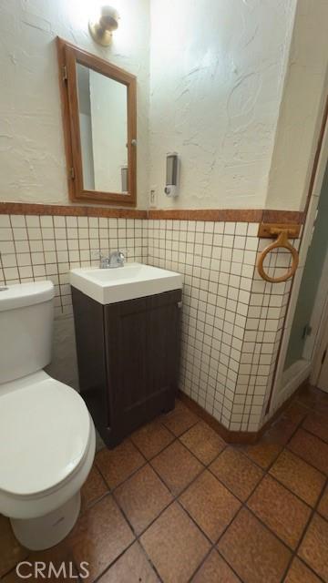 bathroom featuring tile walls, toilet, vanity, and tile patterned flooring