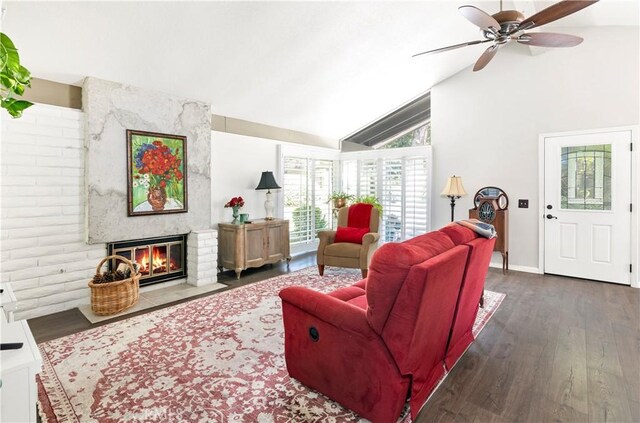 living room with ceiling fan, dark hardwood / wood-style flooring, lofted ceiling, and a large fireplace