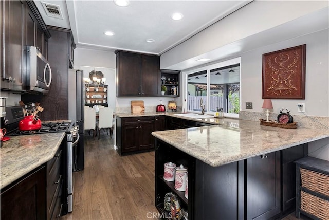 kitchen featuring kitchen peninsula, appliances with stainless steel finishes, dark hardwood / wood-style flooring, light stone counters, and sink