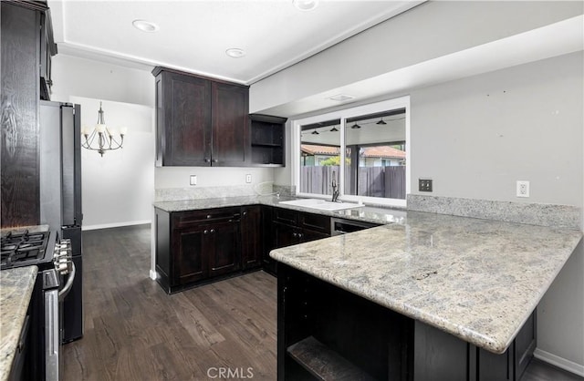 kitchen featuring dark wood-type flooring, a peninsula, stainless steel gas range, open shelves, and a sink