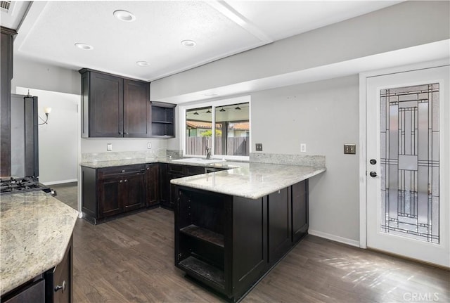 kitchen featuring open shelves, dark wood-type flooring, a sink, dark brown cabinetry, and a peninsula