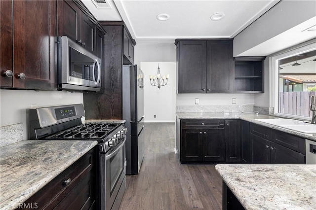 kitchen featuring visible vents, dark wood finished floors, stainless steel appliances, dark brown cabinets, and a sink