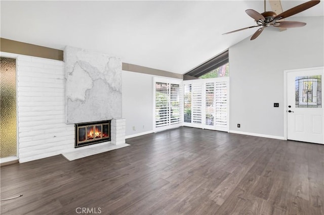 unfurnished living room with ceiling fan, high vaulted ceiling, a large fireplace, wood finished floors, and baseboards