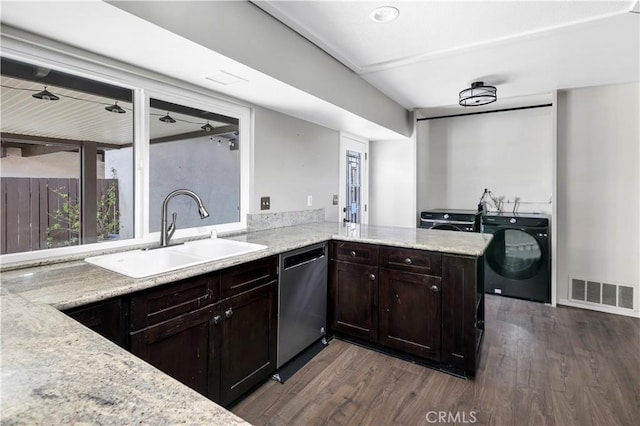 kitchen featuring washing machine and dryer, a sink, visible vents, stainless steel dishwasher, and dark wood finished floors