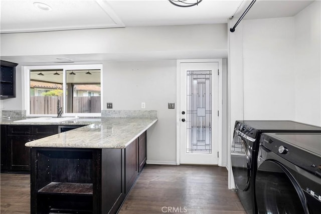 laundry area featuring dark wood-type flooring, independent washer and dryer, a sink, and baseboards