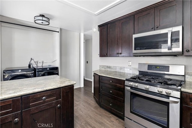 kitchen with appliances with stainless steel finishes, washing machine and dryer, dark brown cabinets, wood finished floors, and baseboards