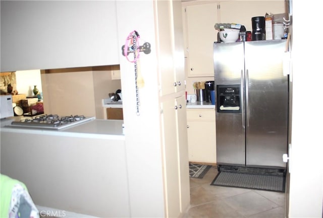 kitchen with light tile patterned floors, white cabinets, stainless steel fridge, and white gas stovetop