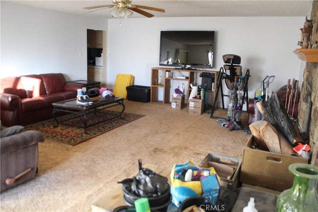 living room with ceiling fan, carpet, and a stone fireplace