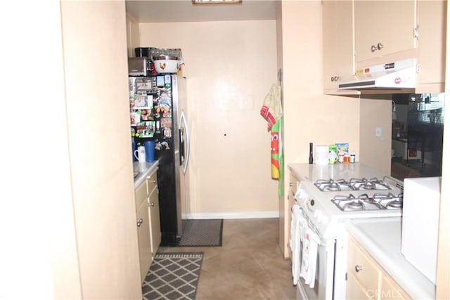 kitchen with cream cabinetry, white gas range oven, extractor fan, and stainless steel refrigerator