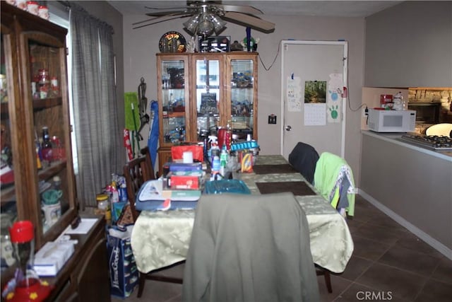 dining room with ceiling fan, a fireplace, and dark tile patterned flooring