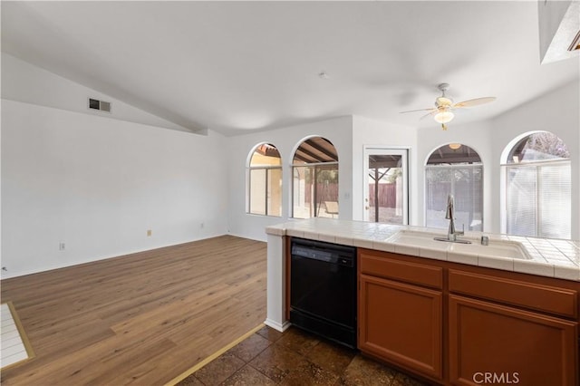 kitchen featuring tile countertops, ceiling fan, black dishwasher, vaulted ceiling, and sink