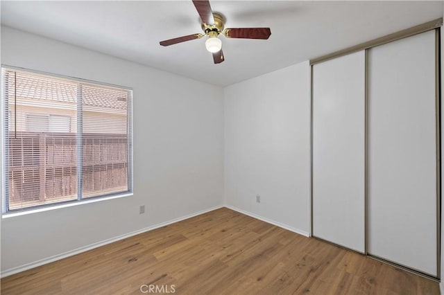 unfurnished bedroom with ceiling fan, a closet, and light hardwood / wood-style floors