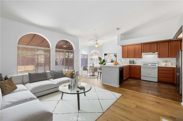 living room featuring vaulted ceiling, ceiling fan, a wealth of natural light, and hardwood / wood-style flooring