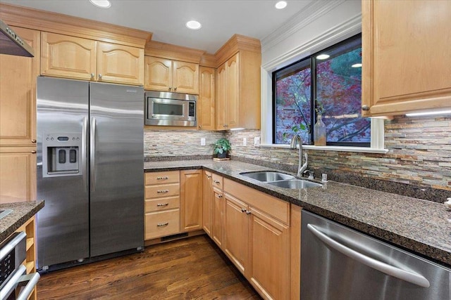 kitchen with appliances with stainless steel finishes, light brown cabinets, dark hardwood / wood-style flooring, dark stone countertops, and sink