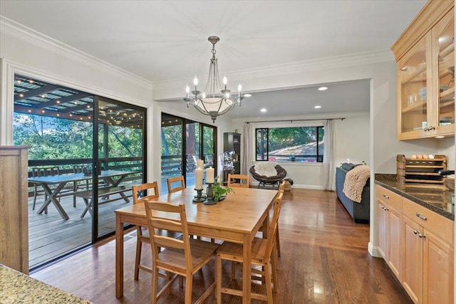 dining space with dark hardwood / wood-style floors, crown molding, and an inviting chandelier