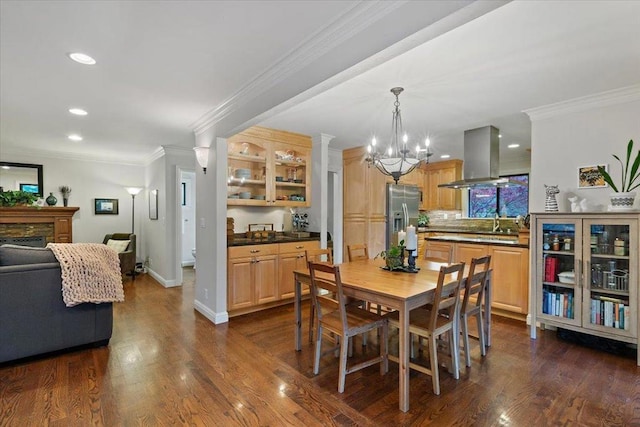 dining space with dark wood-type flooring, crown molding, a fireplace, and an inviting chandelier