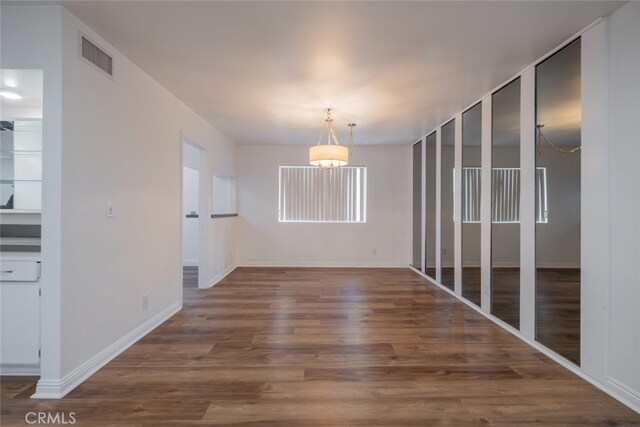 unfurnished dining area featuring dark hardwood / wood-style floors and a chandelier