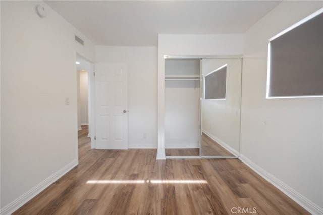 unfurnished bedroom featuring a closet and hardwood / wood-style flooring