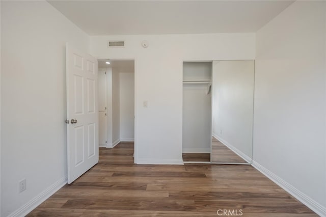 unfurnished bedroom with a closet and dark hardwood / wood-style floors