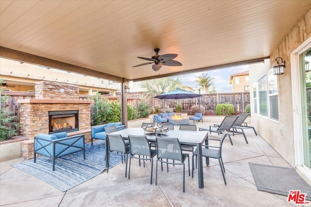 view of patio / terrace featuring ceiling fan and an outdoor living space with a fireplace