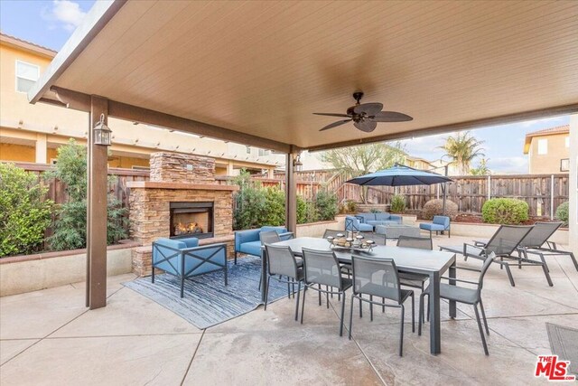 view of patio featuring ceiling fan and an outdoor living space with a fireplace