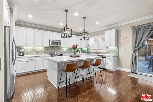 kitchen with white cabinets, appliances with stainless steel finishes, a kitchen island, dark wood-type flooring, and a kitchen breakfast bar